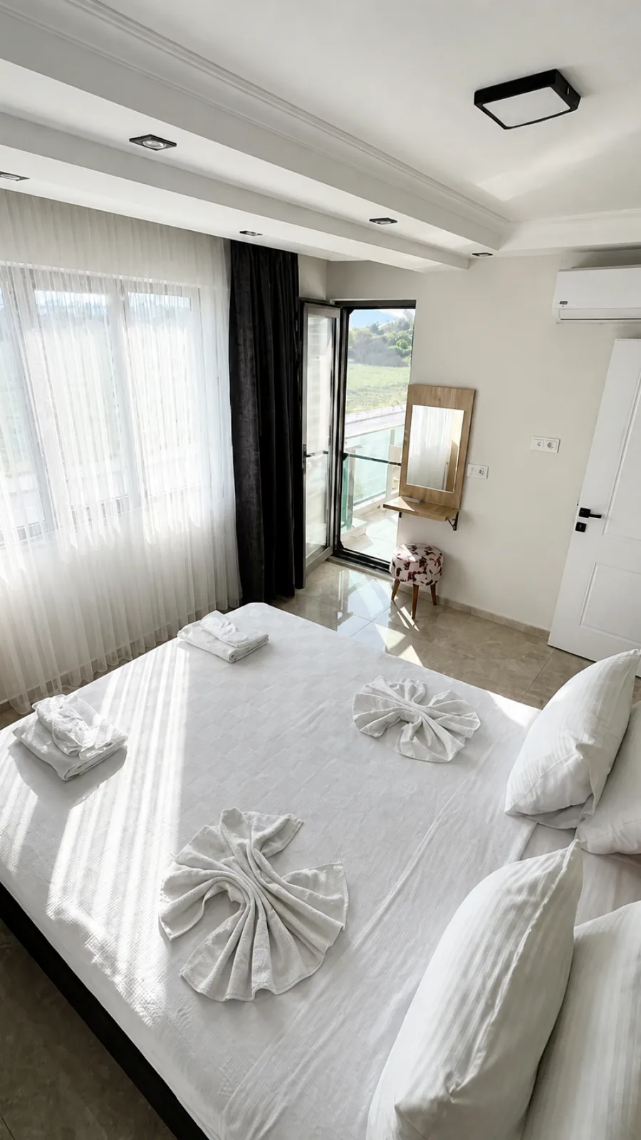 Tepelere açılan balkon kapısı ve hazırlanmış yatağıyla aydınlık misafir odası